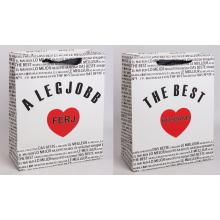 PAPIEROVÁ TAŠKA S MATNOU KLOPOU SO STUHOU, ČIERNY MEDZINÁRODNÝ NÁPIS NA BIELOM POZADÍ, "A LEGJOBB FÉRJ/ THE BEST HUSBAND" S ČERVENÝM SRDCOM