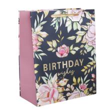 PAPIEROVÁ TAŠKA S MATNOU, LESKLOU POTLAČOU "BIRTHDAY WISHES" V ZLATEJ FARBE S RUŽOVÝMI KVETMI